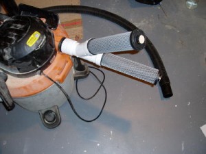 A set of activated carbon tubes are attached to the exhaust of a shop vacuum to filter the air